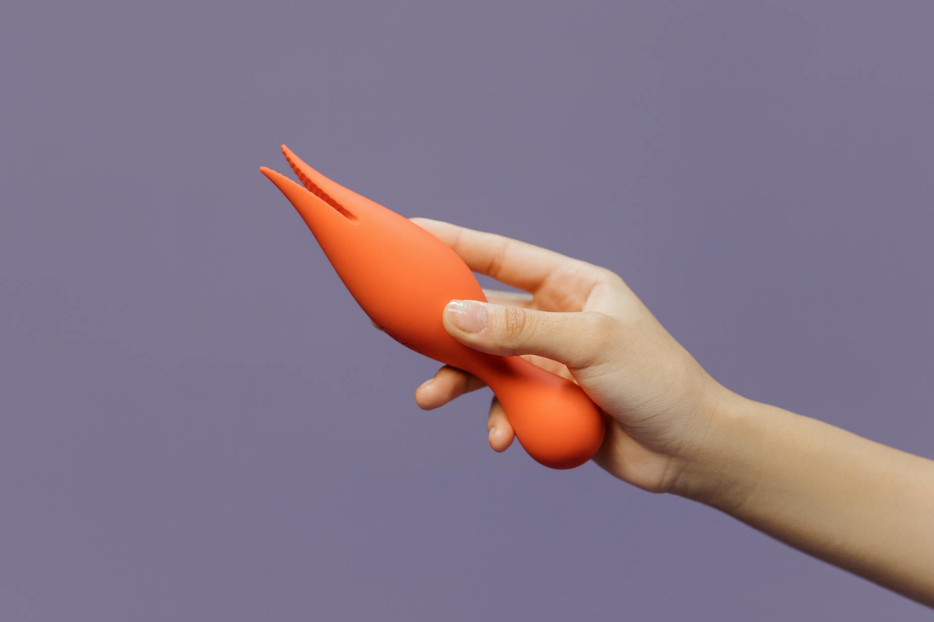 Close-up of a hand holding a vibrator against a purple backdrop, representing modern sensuality and pleasure recovery.