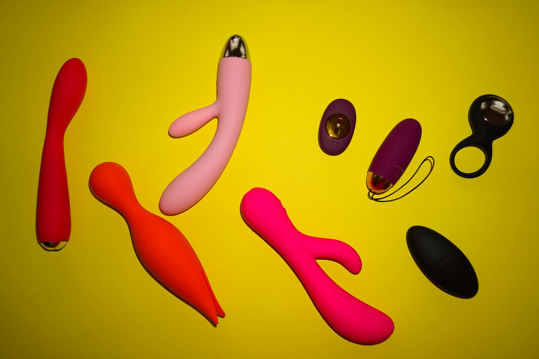 Vibrant collection of colorful clitoral vibrators and lemon suckers displayed on a yellow surface