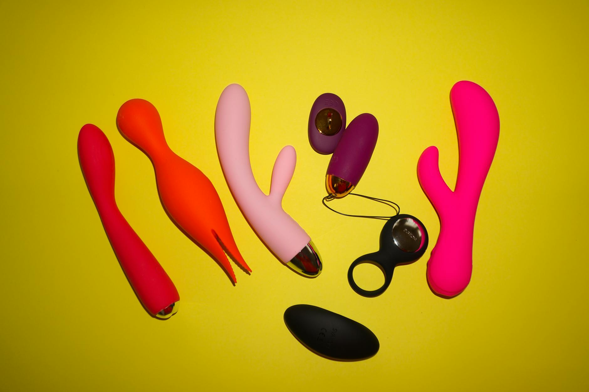Colorful vibrators and intimate toys displayed on a bright yellow background