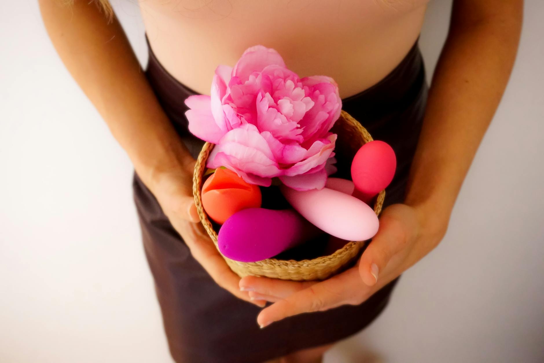 A basket of colorful vibrators and a pink flower representing choices and self-care without judgment